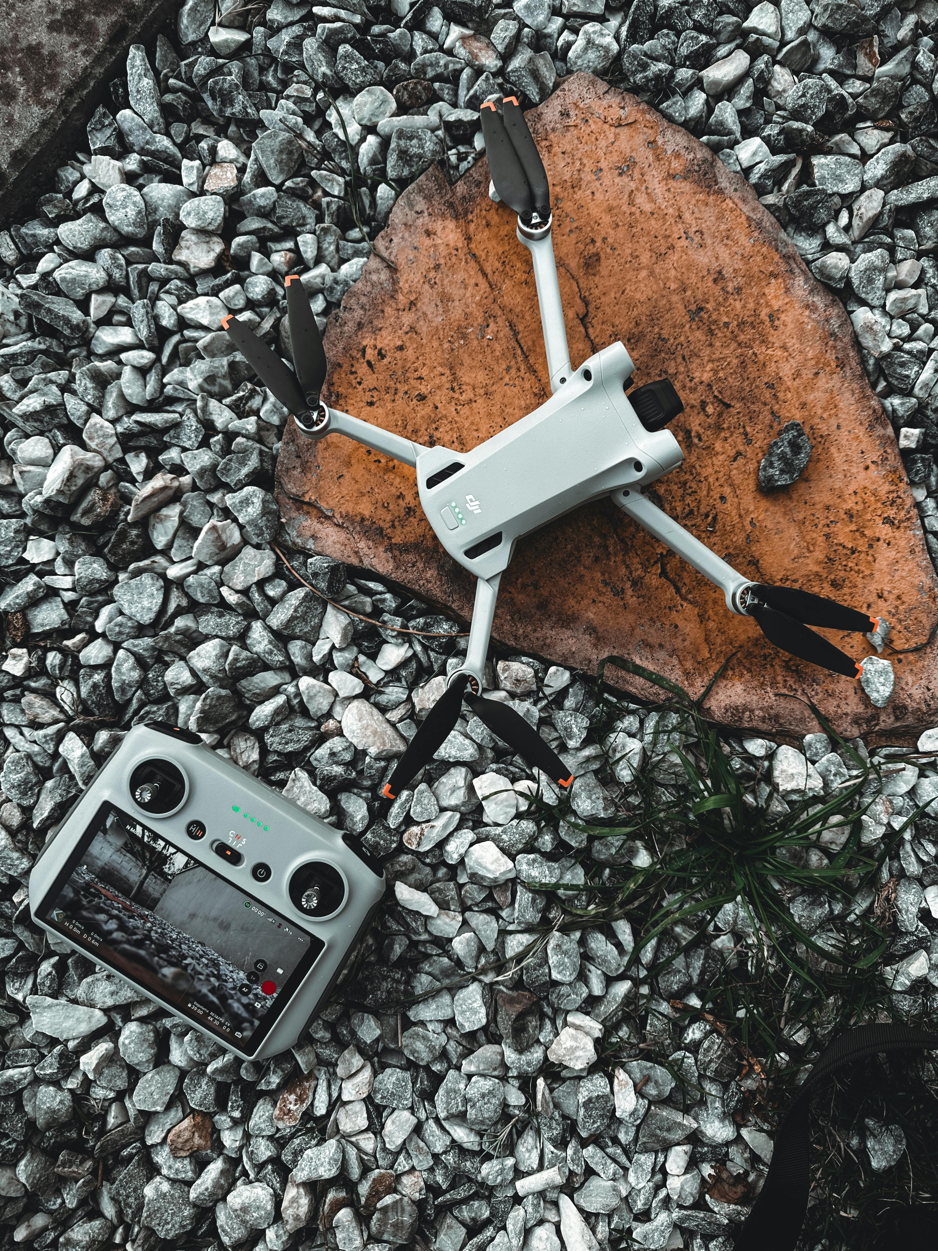 Turkish This image shows a drone and its controller lying on a rocky surface. The drone is white with black propellers, an...