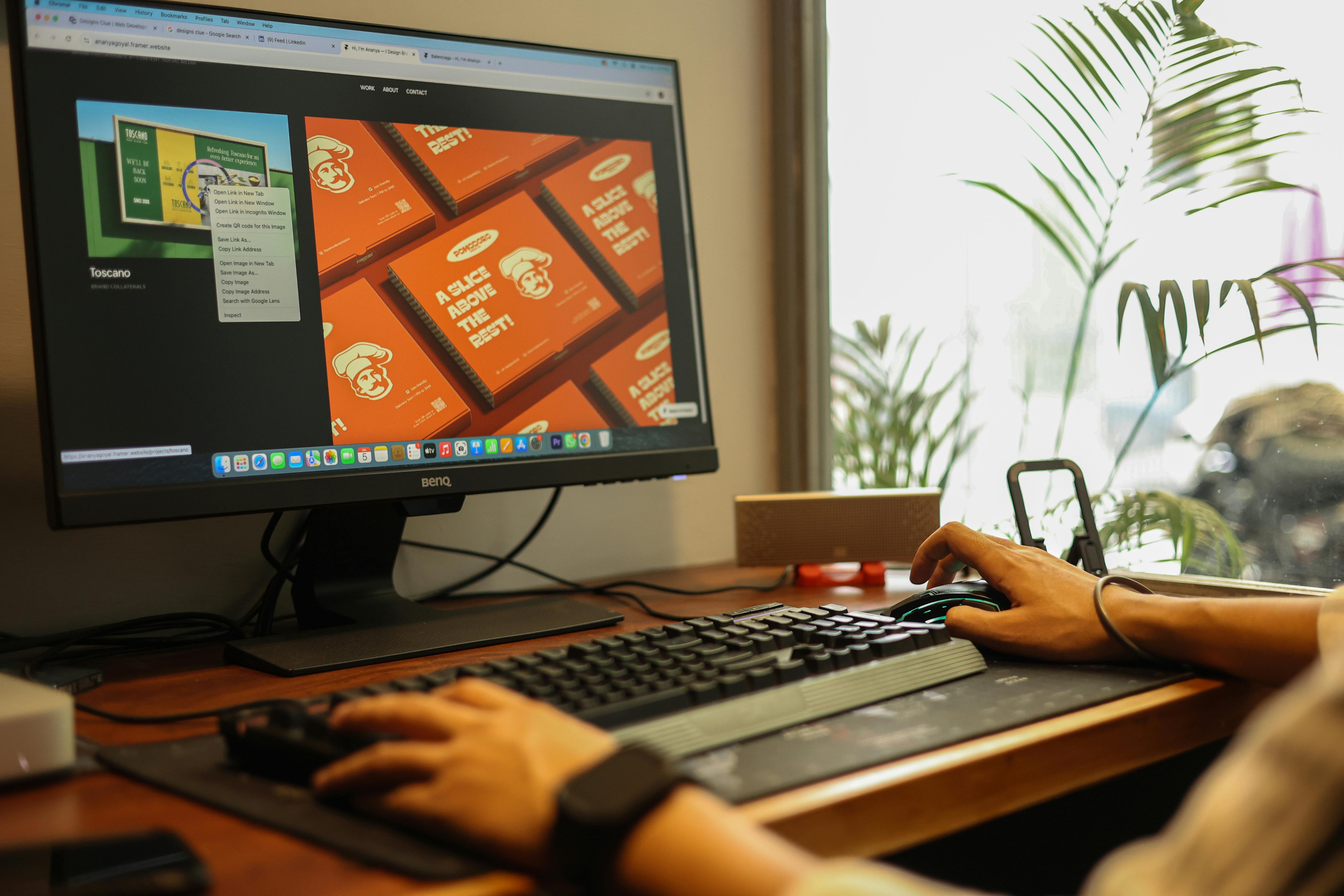 A person is using a computer with a monitor, keyboard, and mouse. The monitor displays a website with various images and t...